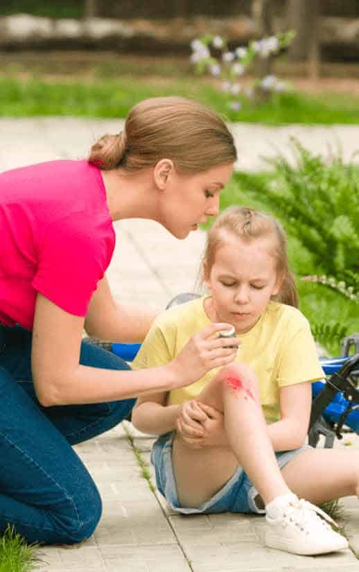 Женщина оказывает первую помощь ребенку после падения с велосипеда